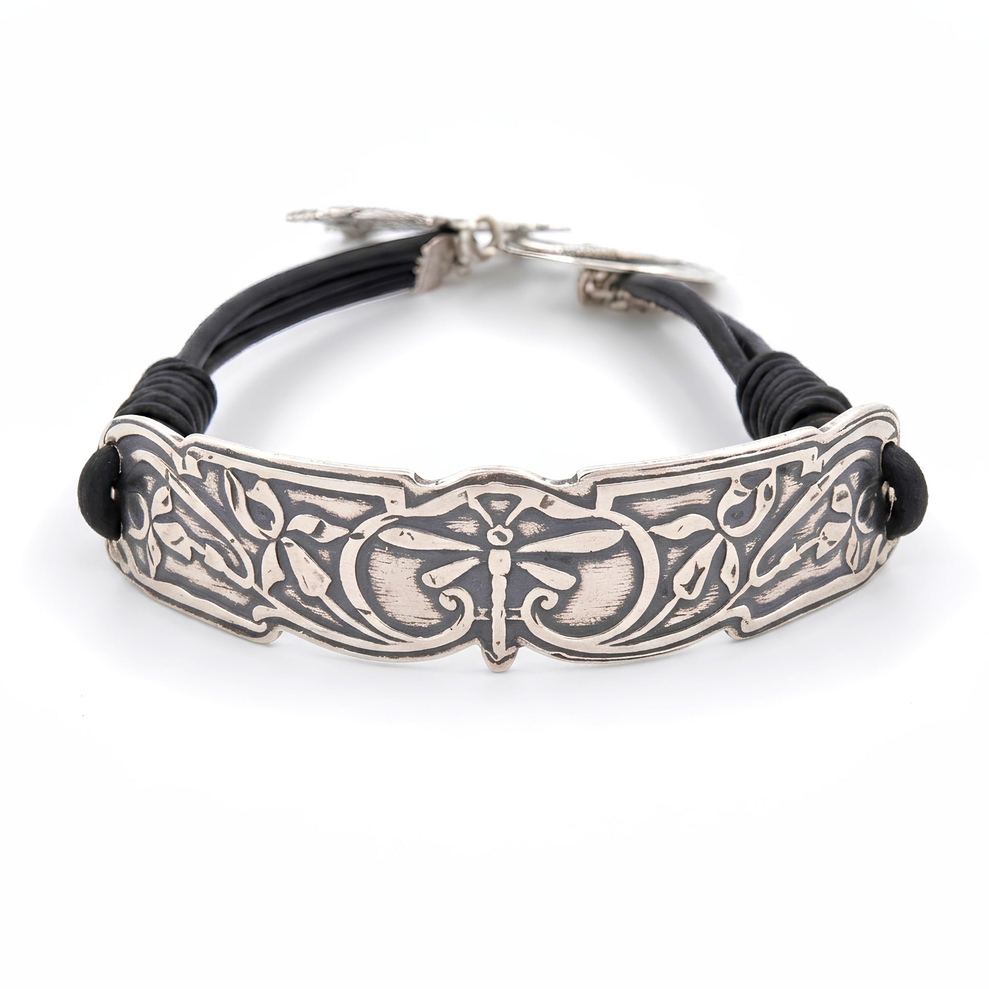 A silver-toned metal bracelet featuring an ornate engraved dragonfly motif, accented by black cord wraps on both sides, shown on a clean white background.