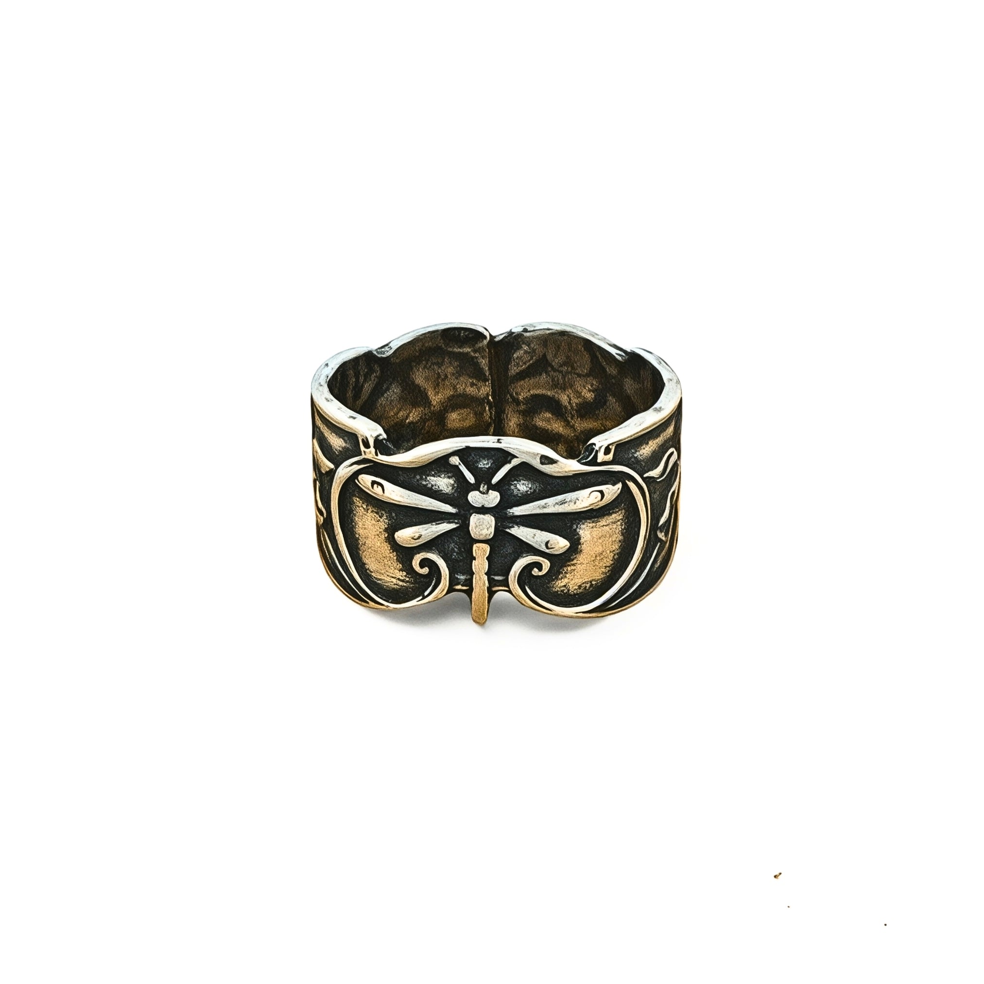 A wide silver-toned ring featuring a dragonfly motif with dark oxidized detailing and a small gold-toned accent at the center, shown on a plain white background.